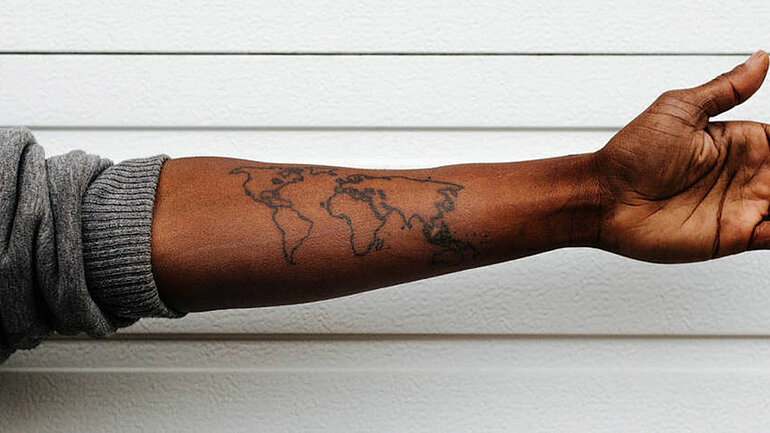 Ein Arm, auf den die Kontinente tätowiert sind