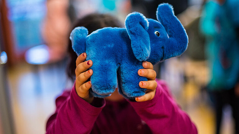 Ein Mädchen hält sich am 08.11.2016 in Mainz (Rheinland-Pfalz) das Maskottchen der Einrichtung "Blauer Elefant" vor das Gesicht. Das Kinderhaus Blauer Elefant ist ein offenes Haus für 6- bis 12-jährige Schulkinder.