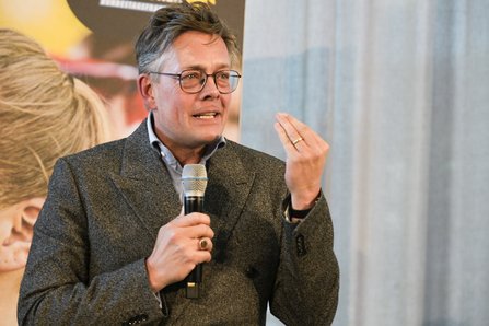 Mann spricht energisch mit erhobener Hand, Mikro 