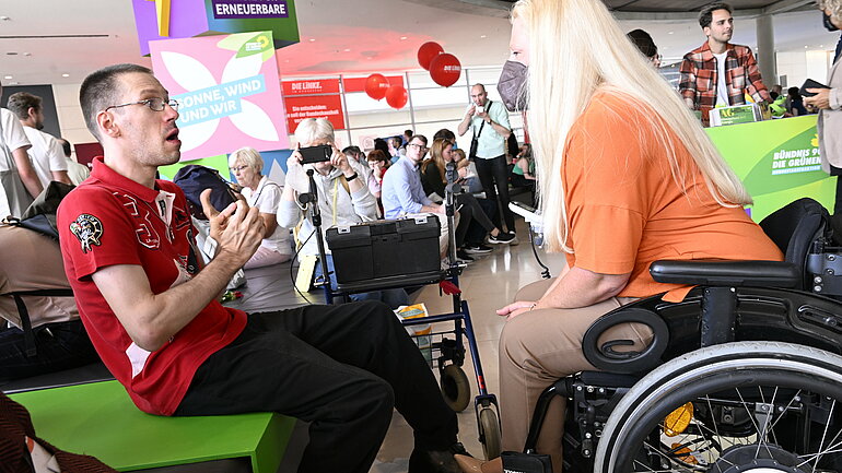 Eine Frau im Rollstuhl spricht mit einem Mann