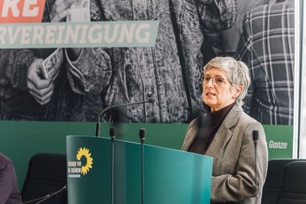Britta Haßelmann MdB am grünen Redepult, fotografiert aus anderer Perspektive. 
