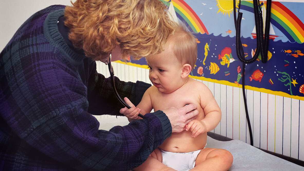 Kinderärztin hört Baby mit Stetoskop ab.
