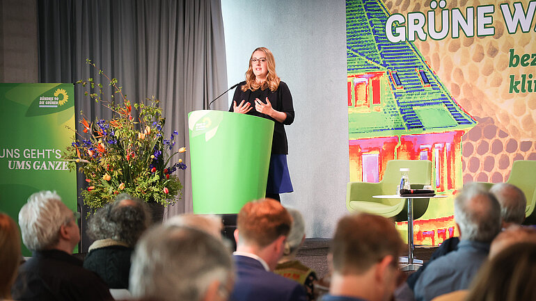Eine Frau, Katharina Dröge, an einem grünen Redepult
