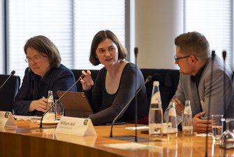Drei Personen in einem Konferenzraum.