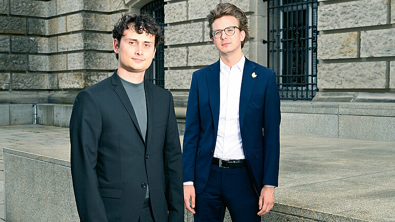 Die Abgeordneten Lukas Benner & Leon Eckert stehen vor dem Bundestag
