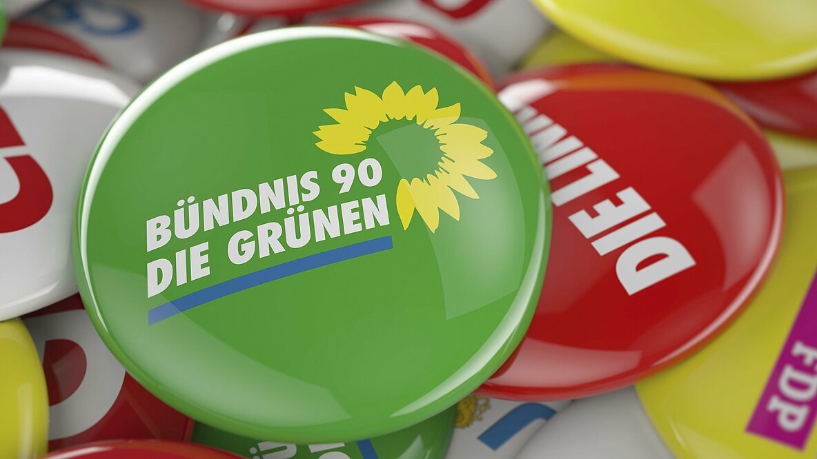 Ein Button von Bündnis 90/Die Grünen, liegt auf den Buttons anderer deutscher Parteien