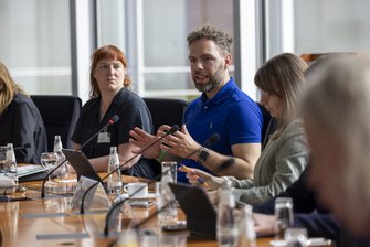 Im Konferenzraum spricht ein Mann in strahlend blauem Hemd.