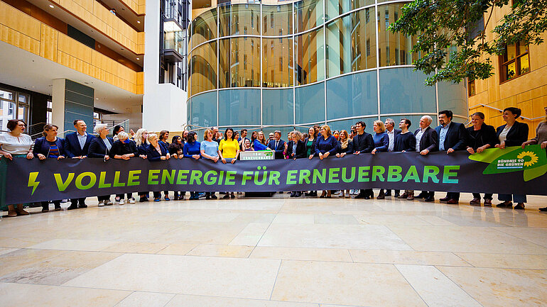 Die grünen Bundestagsfraktion hält das Banner "Volle Energie für Erneuerbare" hoch.