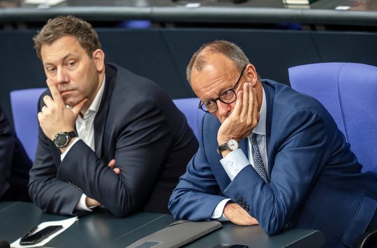 Lars Klingbeil und Friedrich Merz sitzen nebeneinander im Plenum auf der Regierungsbank