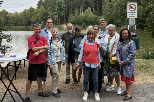 Die grüne Bundestagsabgeordnete Ayse Asar steht mit einer Besuchsgruppe in ihrem Wahlkreis am Beuerbacher See
