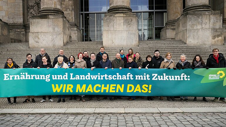 Grüne Bundestagsabgeordnete und weitere Menschen stehen hinter einem grünen Banner mit der Aufschrift "Ernährung und Landwirtschaft mit Zukunft: Wir machen das"