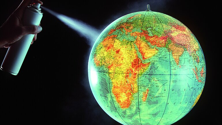 Symbolbild - Zerstörung der Ozonschicht, Plakat auf dem eine Weltkugel mit aus einer Dose besprüht wird.