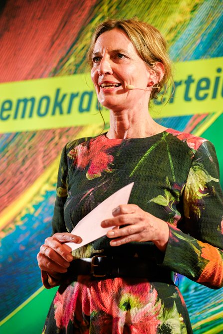 Die Moderatorin Tanja Samrotzki steht mit Headset und Karten in der Hand auf der Bühne
