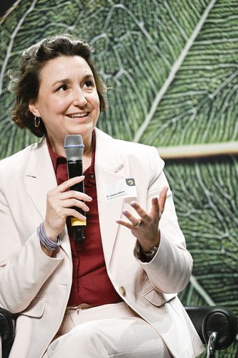 Eine Frau in heller Businesskleidung spricht auf der Bühne