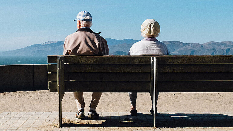 Eine älterer Mann und eine ältere Frau sitzen auf einer Bank