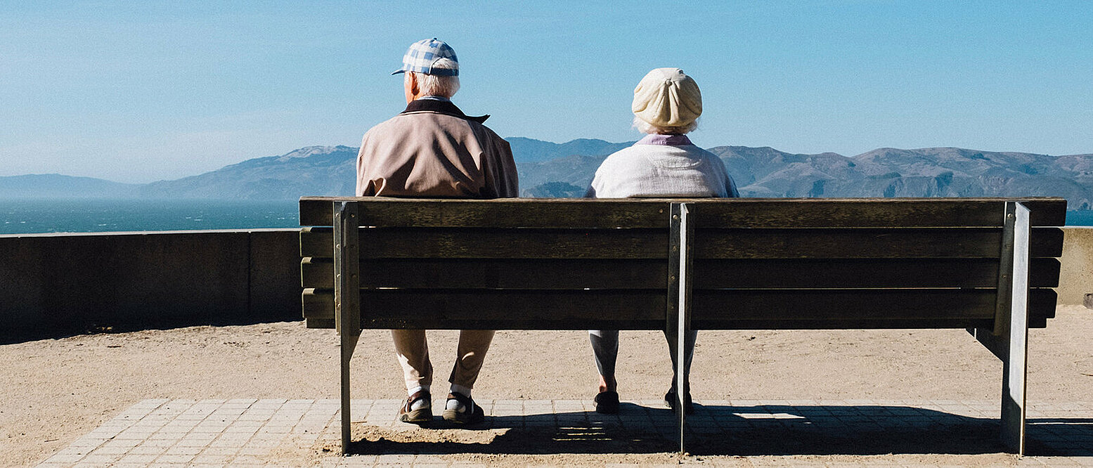 Eine älterer Mann und eine ältere Frau sitzen auf einer Bank