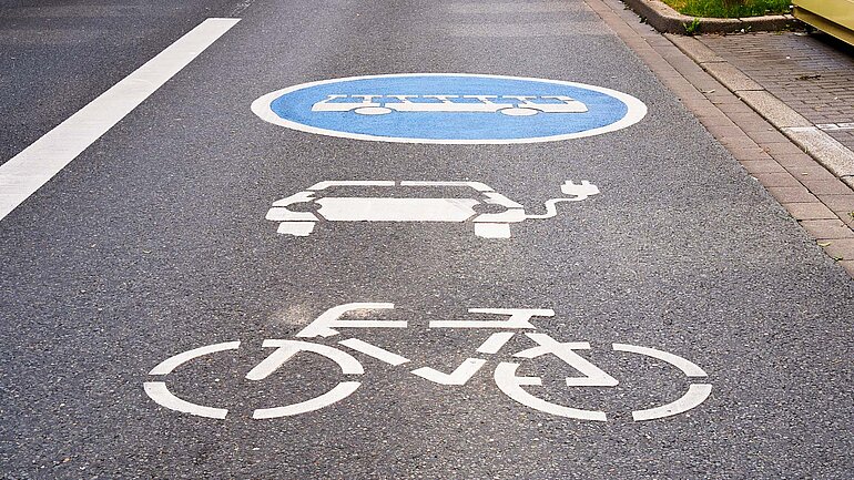 Fahrbahnmarkierungen weisen eine Spur für Fahrrad, Elektromobil und Bus aus.