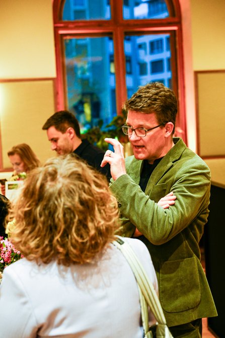 Ein Mann im grünen Jackett unterhält sich