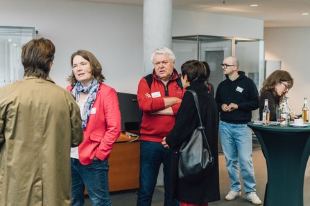 Das Bild zeigt mehrere Personen im Vorraum des Europasaals. Darunter Andrea Lübcke MdB im Gespräch mit Teilnehmenden