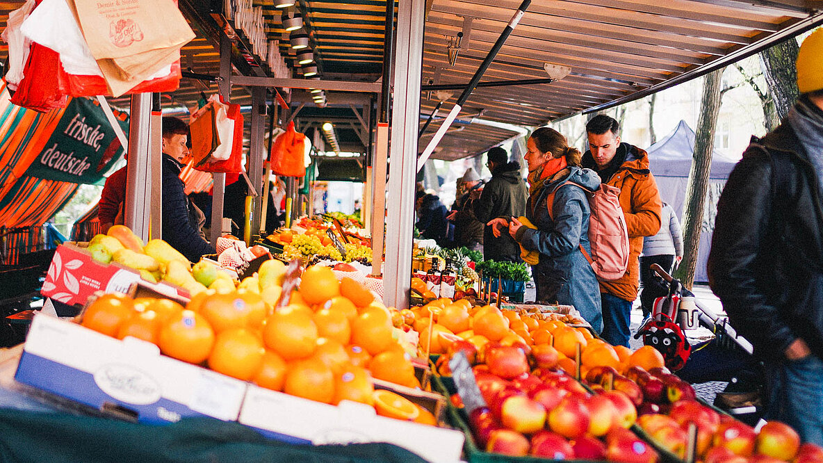 Obst und Menschen an einem Marktstand.