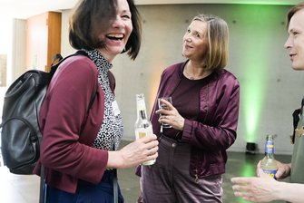 3 Personen unterhalten sich, eine von ihnen lacht herzlich.