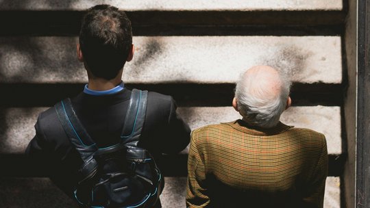 Zwei Männer, einer jünger, der andere älter, gehen nebeneinander eine Treppe hoch