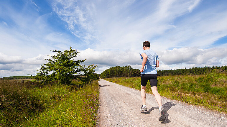 Ein Mann joggt auf einem Feldweg
