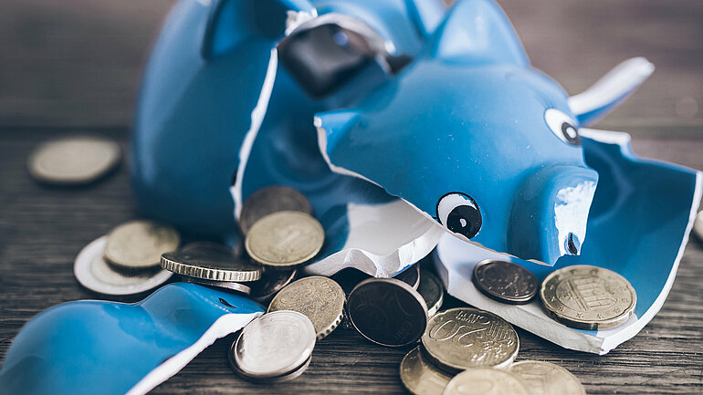 Zerbrochenes blaues Sparschwein mit Euro-Münzen