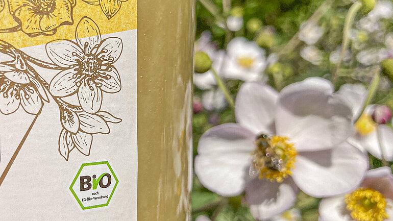 Eine Biene auf einer Blüte, im Vordergrund ein Glas Honig mit dem Biosiegel im Anschnitt. Die Nachfrage nach Bio-Lebensmitteln nimmt seit Jahren zu, doch unter der Großen Koalition wurde der Ökolandbau sträflich vernachlässigt. Das müssen wir ändern.
