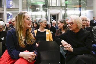 Zwei Personen unterhalten sich in der ersten Reihe des Publikums