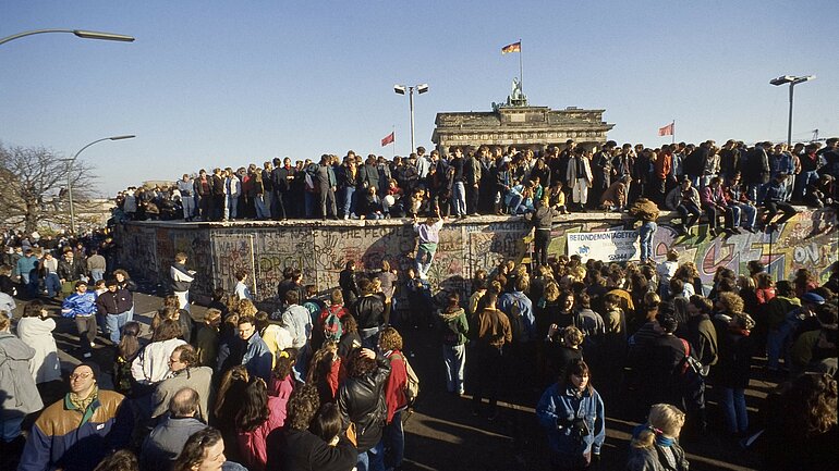 Eine Menschenmenge vor und auf der Mauer 1989 vor dem Brandenburger Tor