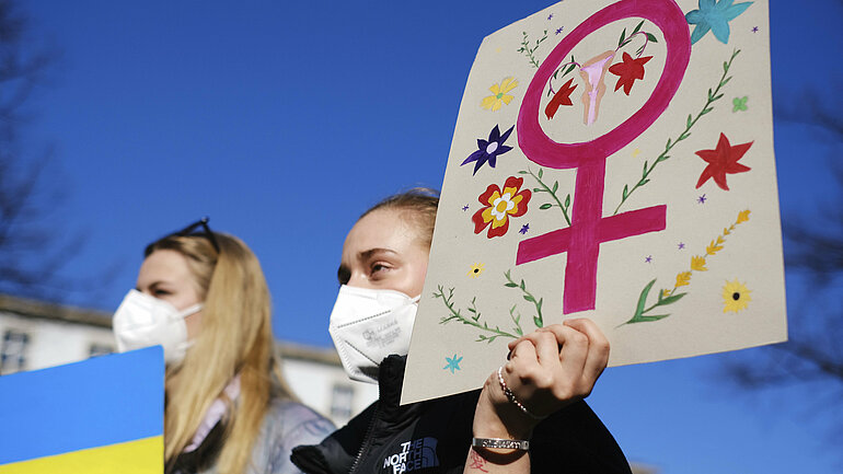 Frauen halten ein Plakat mit dem Symbol für Weiblichkeit auf einer Demo in Berlin.