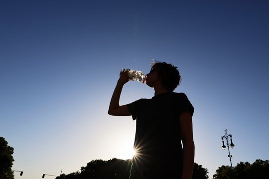 Eine Passantin trinkt Wasser aus einer Plastikflasche.