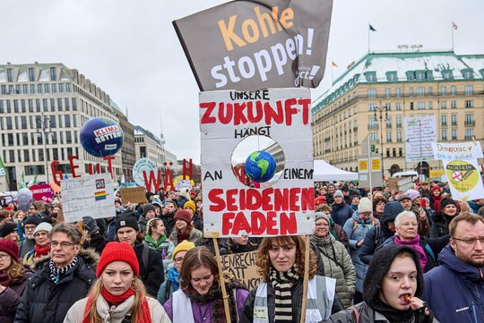 Auf dem pariser Platz demonstrieren junge menschen. auf einem plakat steht: unsere zukunft hängt an einem seidenen faden