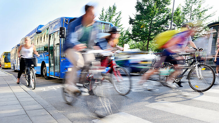 Radfahrende fahren vor Bussen durch den regen Verkehr
