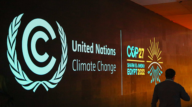Logo der Weltklimakonferenz COP 27 auf einer braunen Wand. 