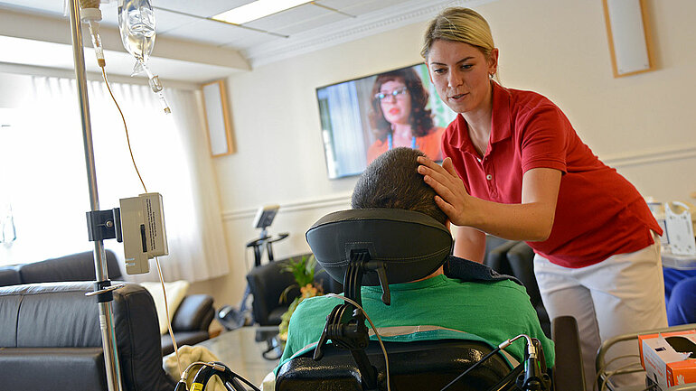 Eine Pflegerin hilft einer Person im Rollstuhl