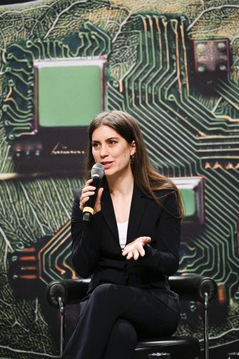 Eine Frau in eleganter Businesskleidung spricht auf der Bühne