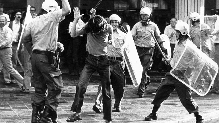 Eine der brutalsten Auseinandersetzungen der letzten Jahre haben sich nach Angaben eines Polizeisprechers Demonstranten und Polizei am 10.5.1976 in Frankfurt am Main bei einem verbotenen Protestmarsch zum Tod der RAF-Terroristin Ulrike Meinhof geliefert. Ulrike Meinhof hatte sich am 5.5.1976 in ihrer Zelle in Stuttgart Stammheim das Leben genommen hatte. Nach dem Versuch der Polizei, die Demonstration mit ca. 600 Teilnehmern aufzulösen, warfen die Demonstranten Molotow- Cocktails und Steine auf die Polizisten und errichteten Barrikaden. Die Polizei setzte Knüppel und Wasserwerfer ein. Über ein Dutzend Polizisten sollen verletzt worden sein, sieben Demonstranten wurden verhaftet. 