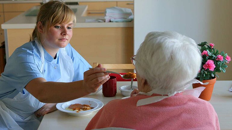 DRK-Seniorenwohnanlage in Rostock-Evershagen, eine Pflegekraft hilft einer Bewohnerin beim Essen.