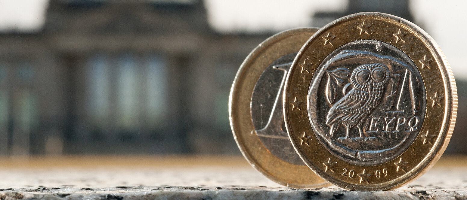 Eine 1-Euro-Münze, im Hintergrund der Reichstag