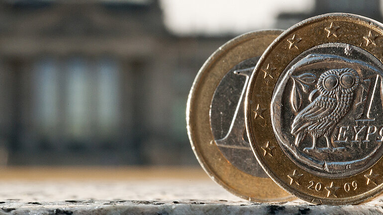 Eine 1-Euro-Münze, im Hintergrund der Reichstag