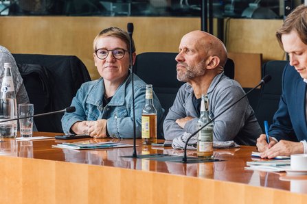 Neben einer weiteren Person ist Simone Fischer MdB im Kreis der Teilnehmenden abgebildet, angeschnitten ist außerdem Dr. Heiko Knopf zu erkennen