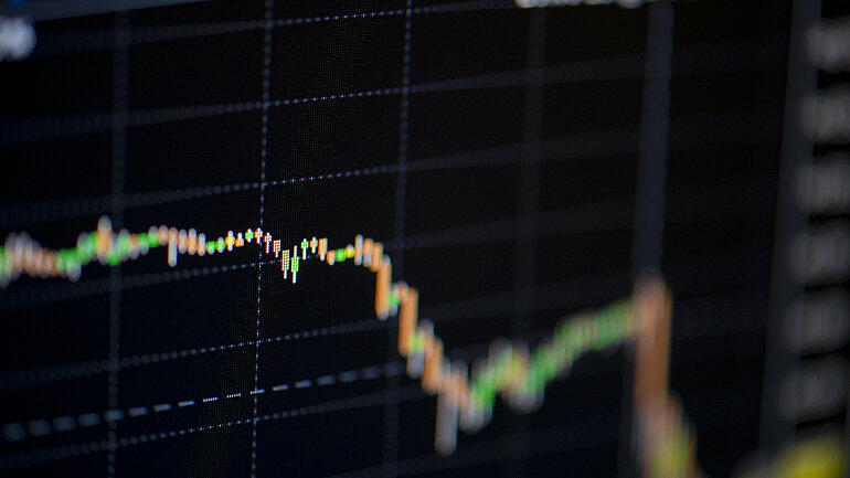 Aktienchart auf einem schwarzen Bildschirm, der sinkenden Aktienkurs anzeigt. 