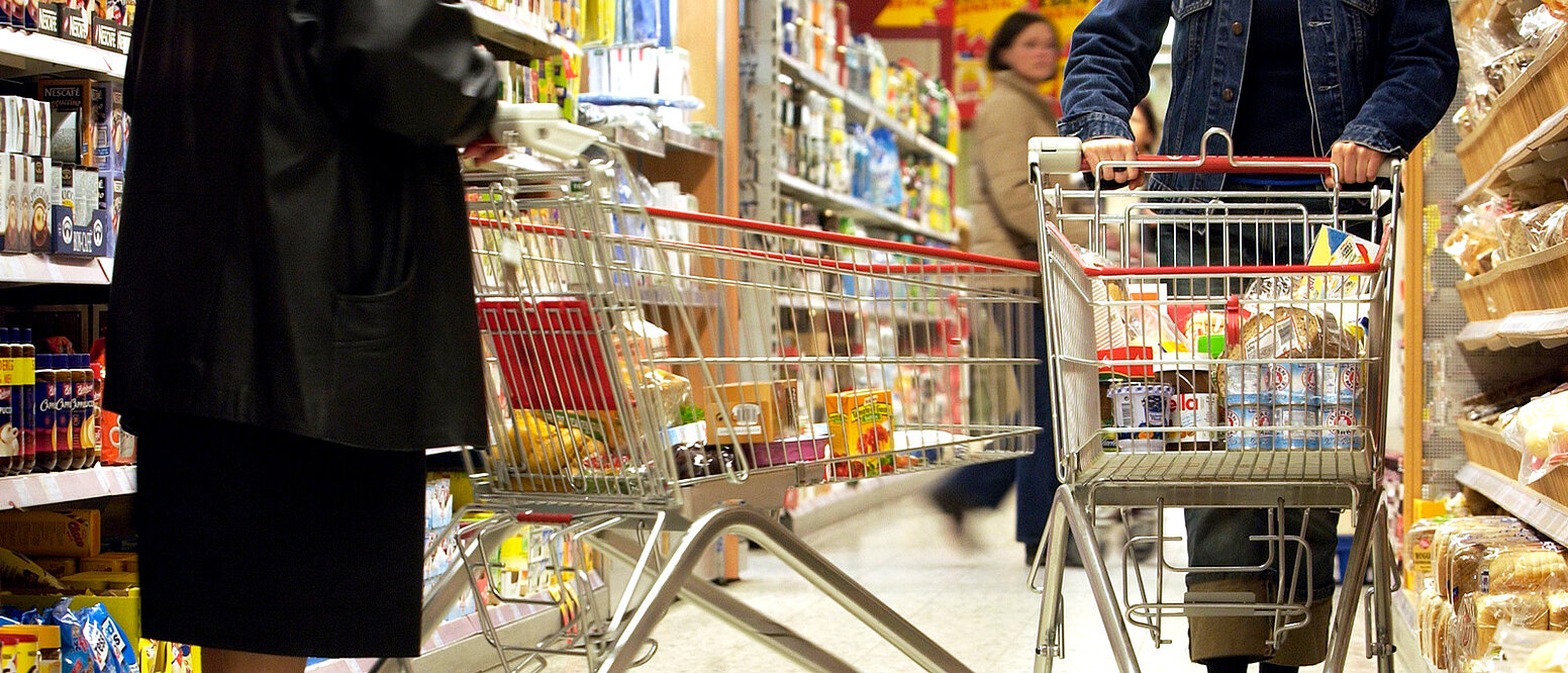 Kunden schieben Einkaufswagen in einem Supermarkt.