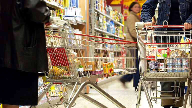 Kunden schieben Einkaufswagen in einem Supermarkt.