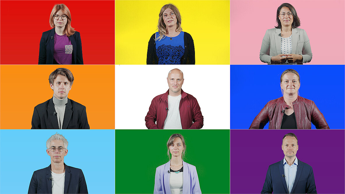 Neun Abgeordnete, die sich für Queer-Themen engagieren, vor Kacheln in Regenbogenfarben..