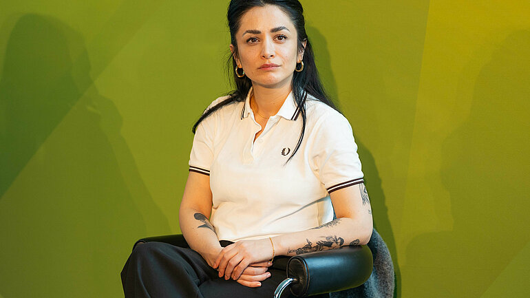 Die Regisseurin Milena Aboyan sitzt vor einer grünen Wand.