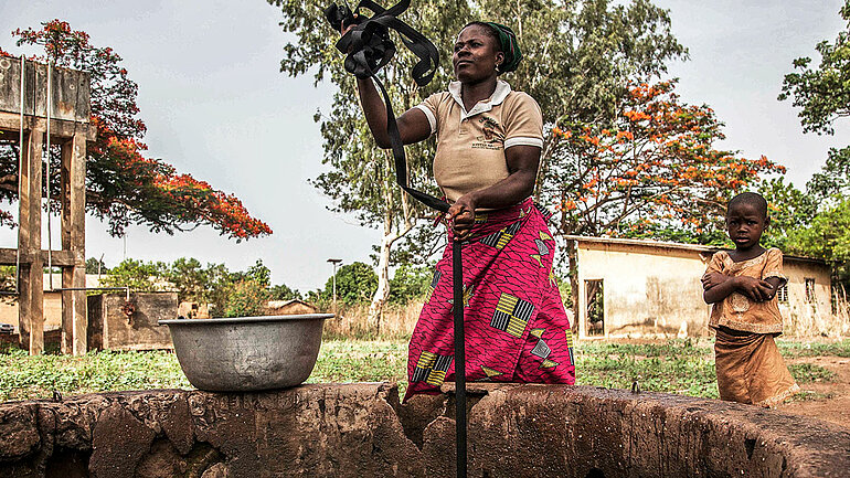 Eine Frau in Benin, Afrika, holt Wasser aus einem Trinkwasserbrunnen.