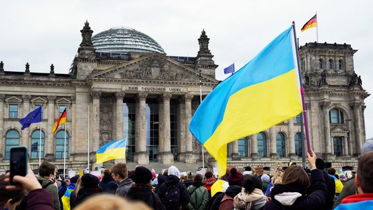 Eine Demonstration vor dem Reichstagsgebäude in Berlin, eine große Ukraine-Flagge weht.